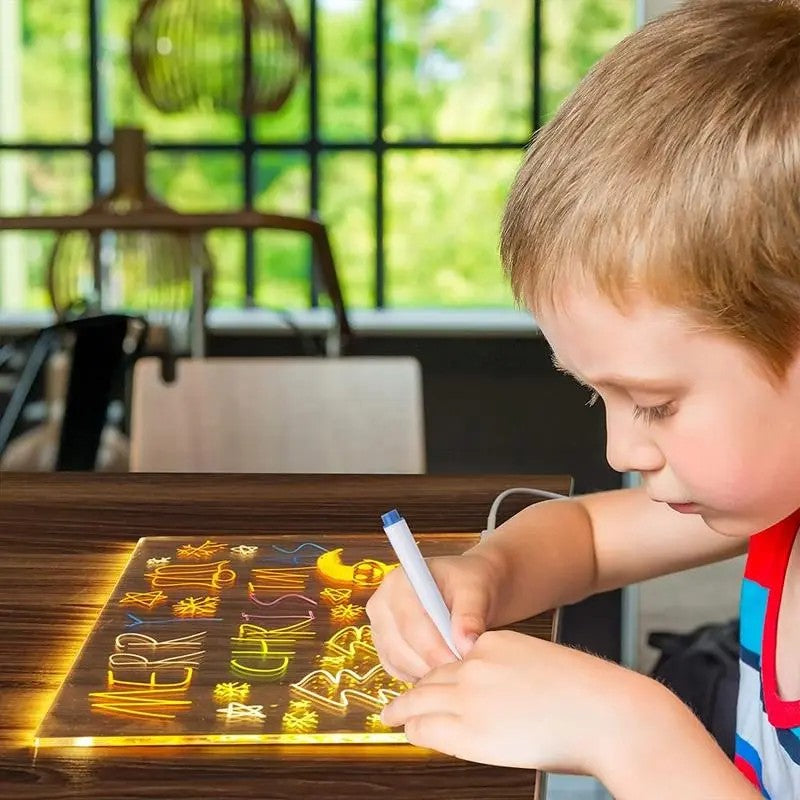 Child writing on a transparent board with letters projected onto it, in a bright room.