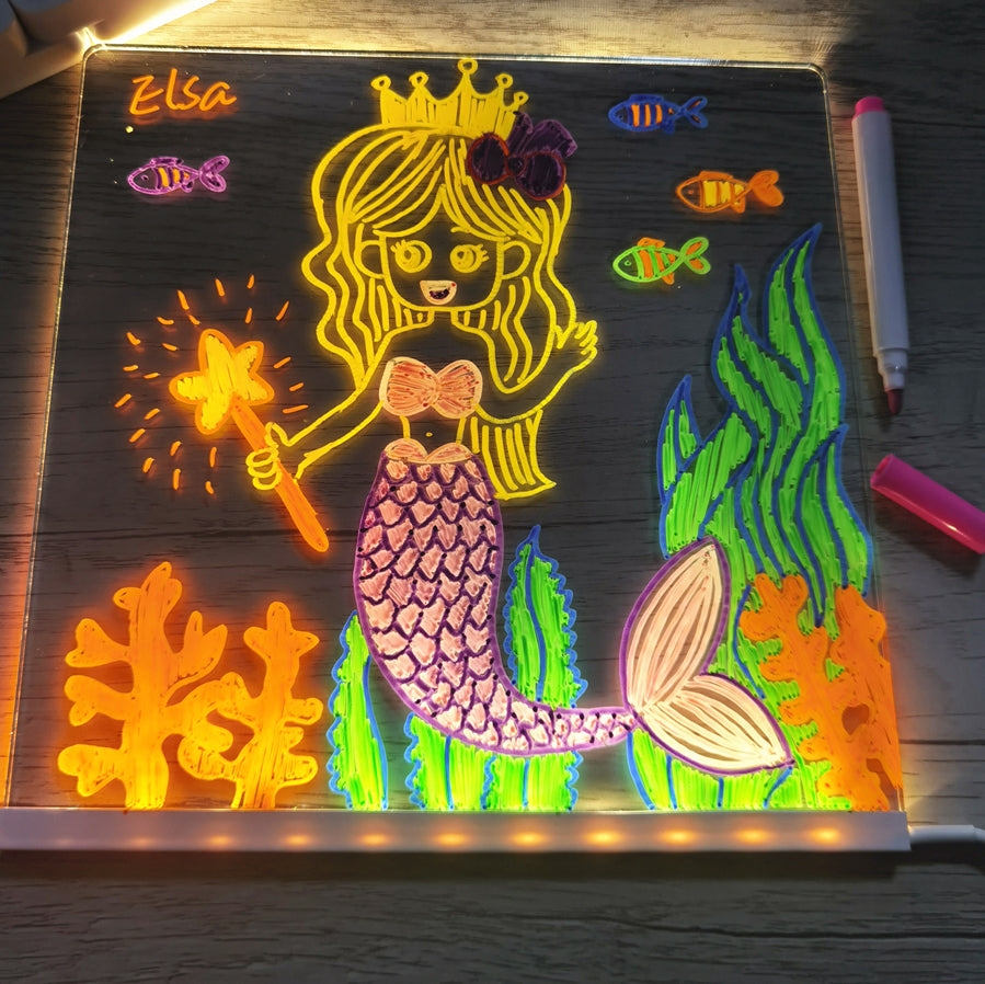Colorful mermaid drawing on a light-up board with markers around.