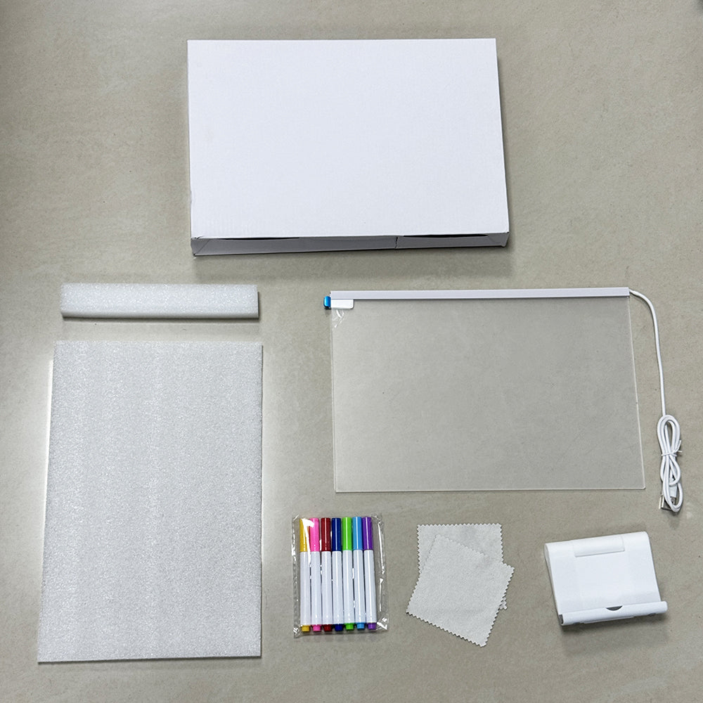 Collection of stationery items including a notebook, markers, a light, and cleaning cloth on a gray surface.