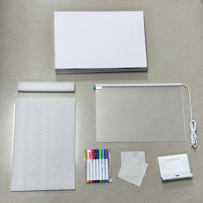 Collection of stationery items including a notebook, markers, a light, and cleaning cloth on a gray surface.